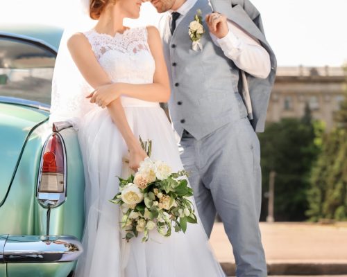 Newly weds leaning on light blue car. They took out an unsecure loan to fund the wedding.